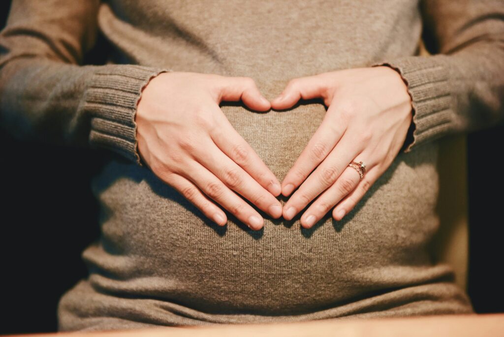 pregnant woman holding her hands in a heart shape over her tummy
